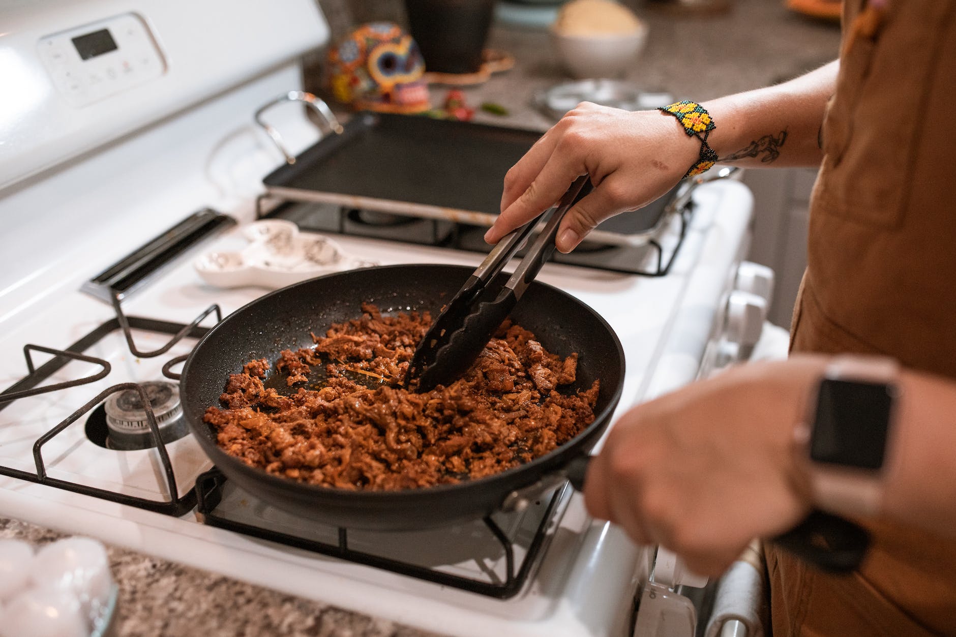 a person cooking while holding a pan and tongs